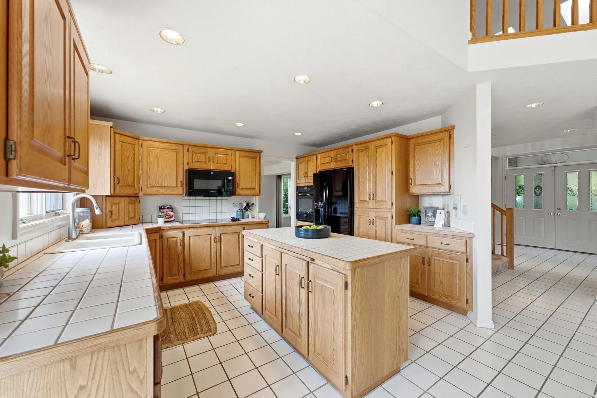 Kitchen featuring wood cabinetry, white tiled countertops, a tiled backsplash, and recessed lighting