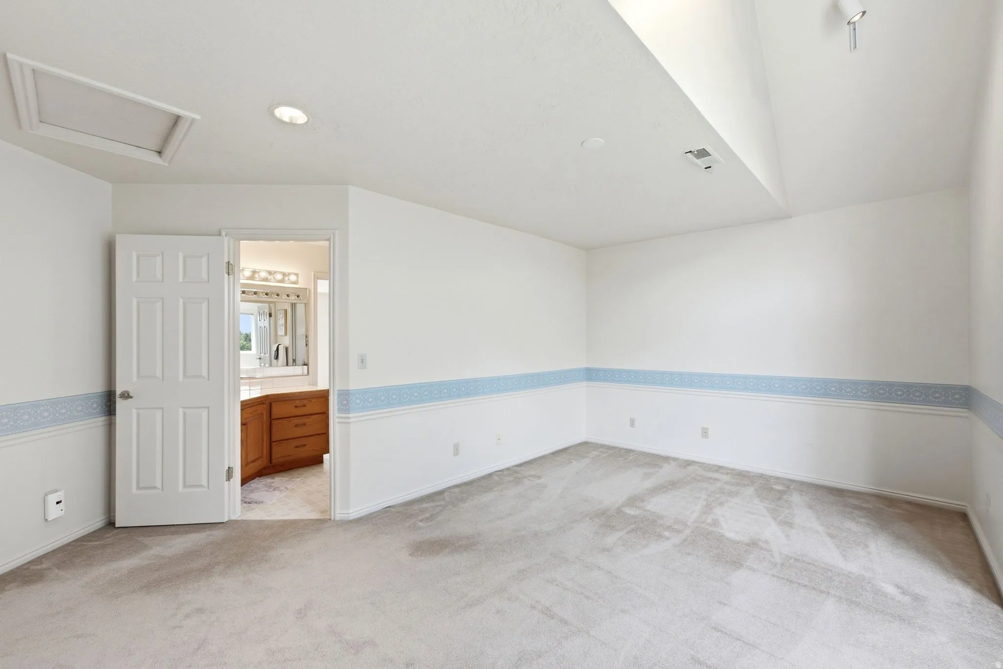 Spacious room featuring neutral carpeting and a decorative wall border