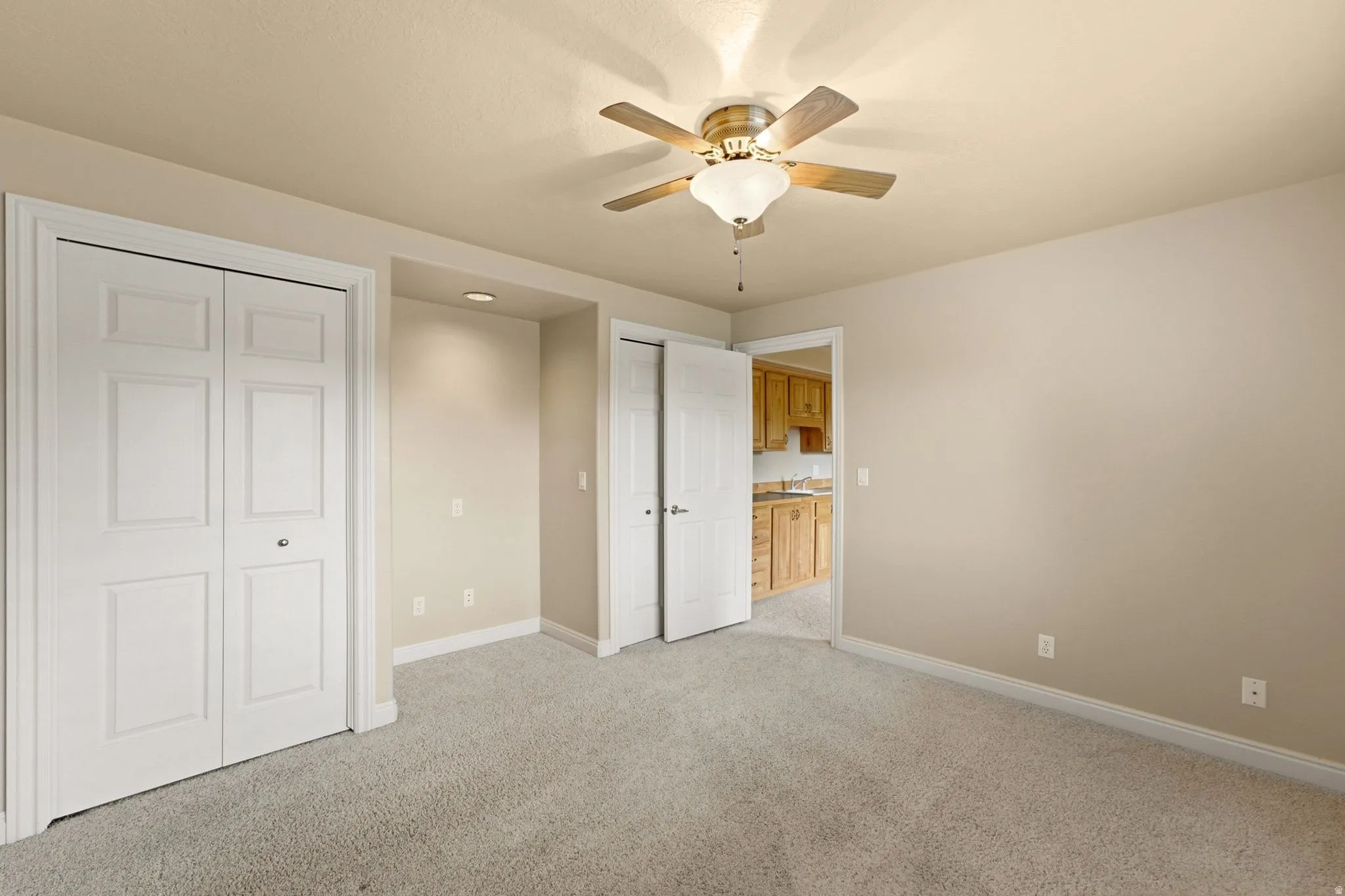 Recessed lighting illuminates an alcove, complementing the overhead ceiling fan with light fixture