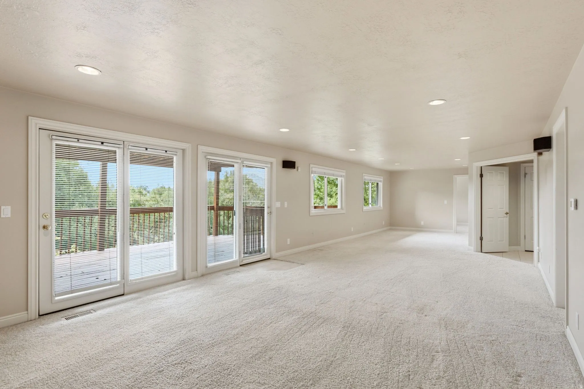 Spacious room featuring multiple glass panel doors opening to an exterior deck