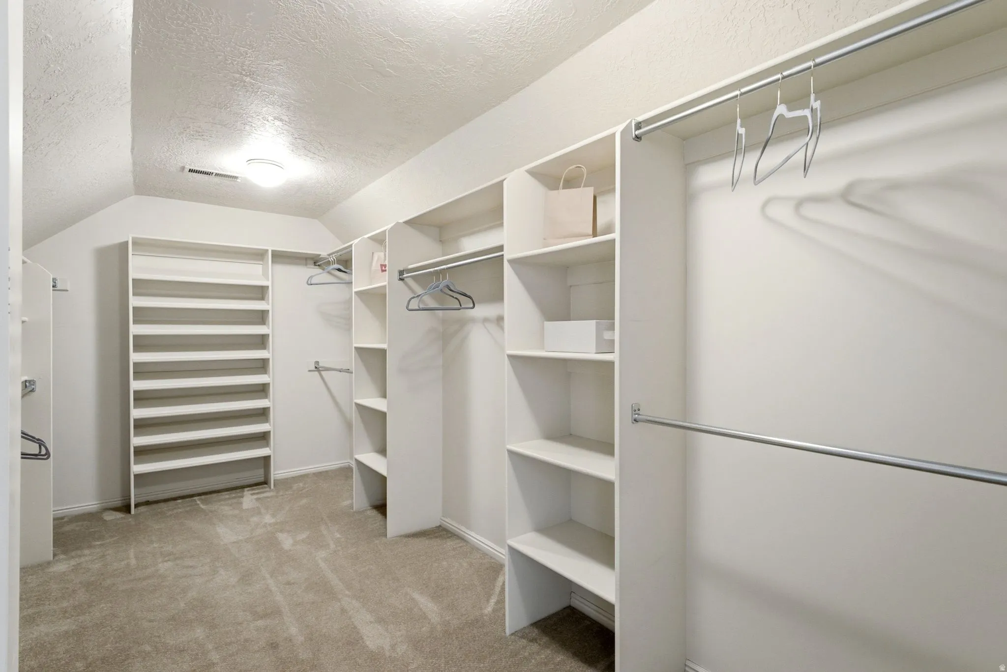 Spacious walk-in closet featuring extensive built-in shelving, multiple hanging rods, and integrated shoe racks