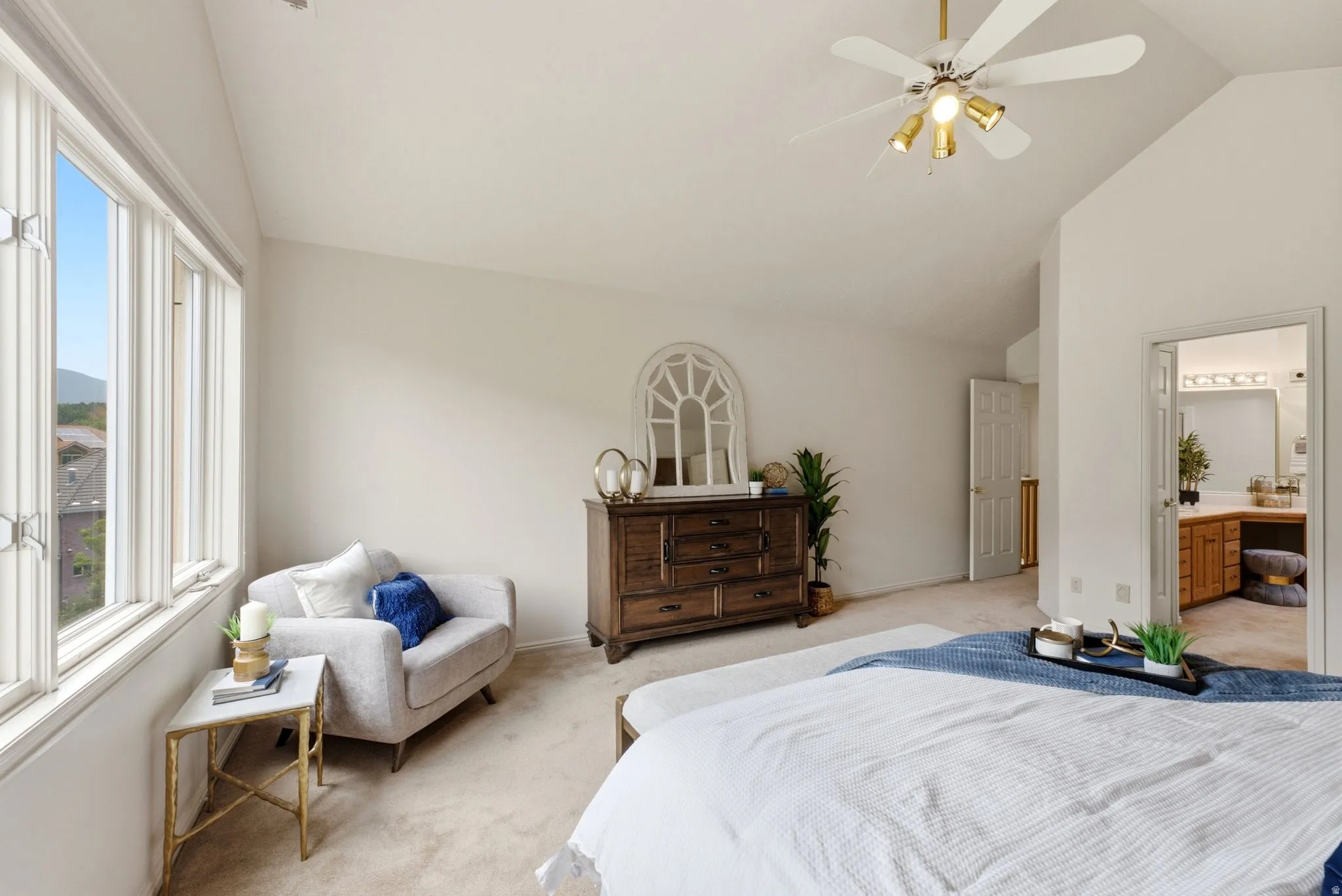 Bright bedroom featuring a wall of tall windows, vaulted ceiling with a ceiling fan, and plush carpeting