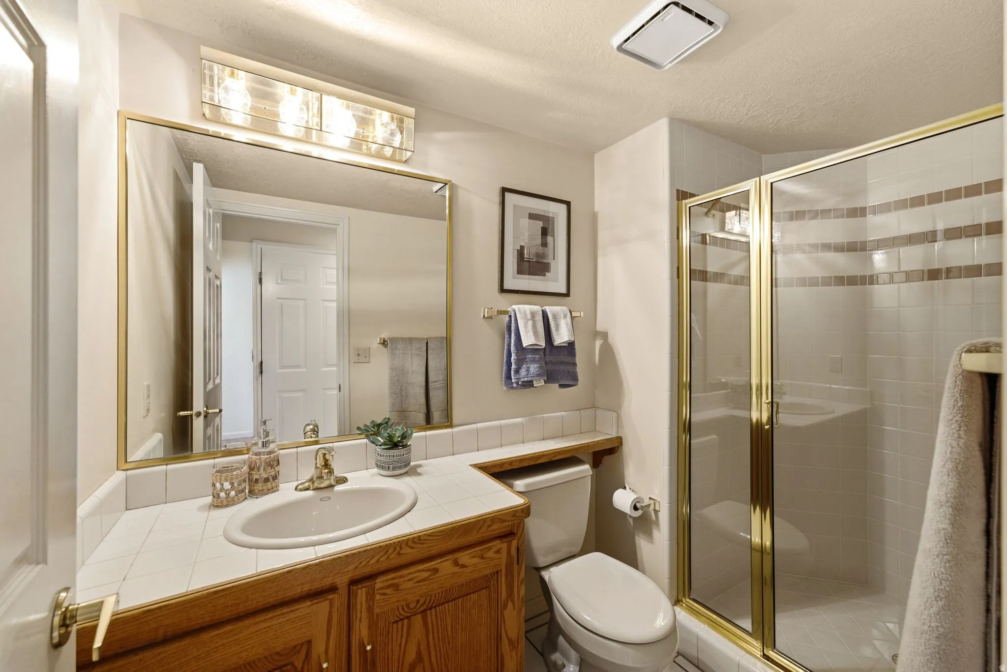 Vanity with wood cabinetry, tile countertop, and a drop-in sink