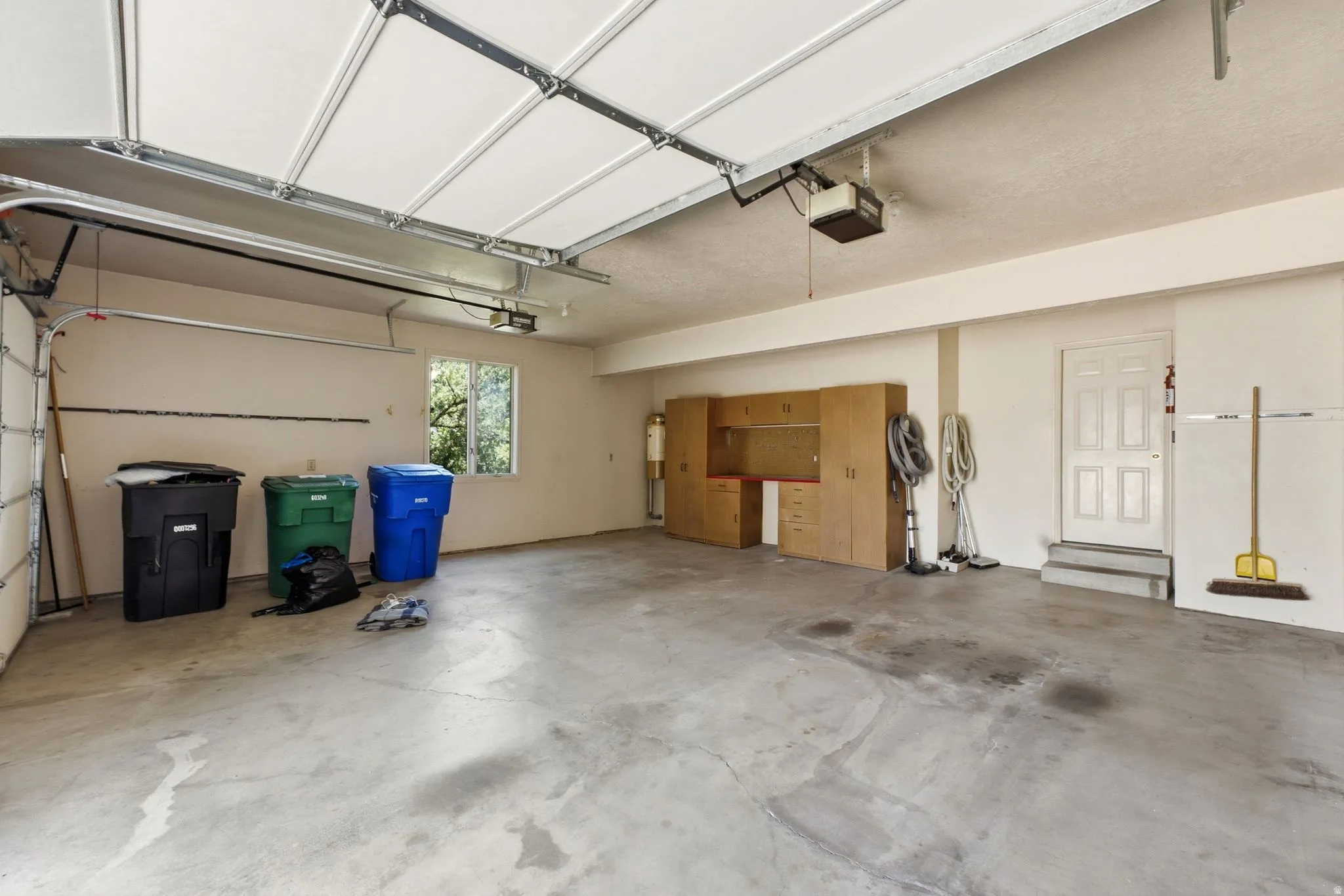 Spacious garage featuring a paneled overhead door, built-in cabinetry, a utility sink, and a multi-pane window