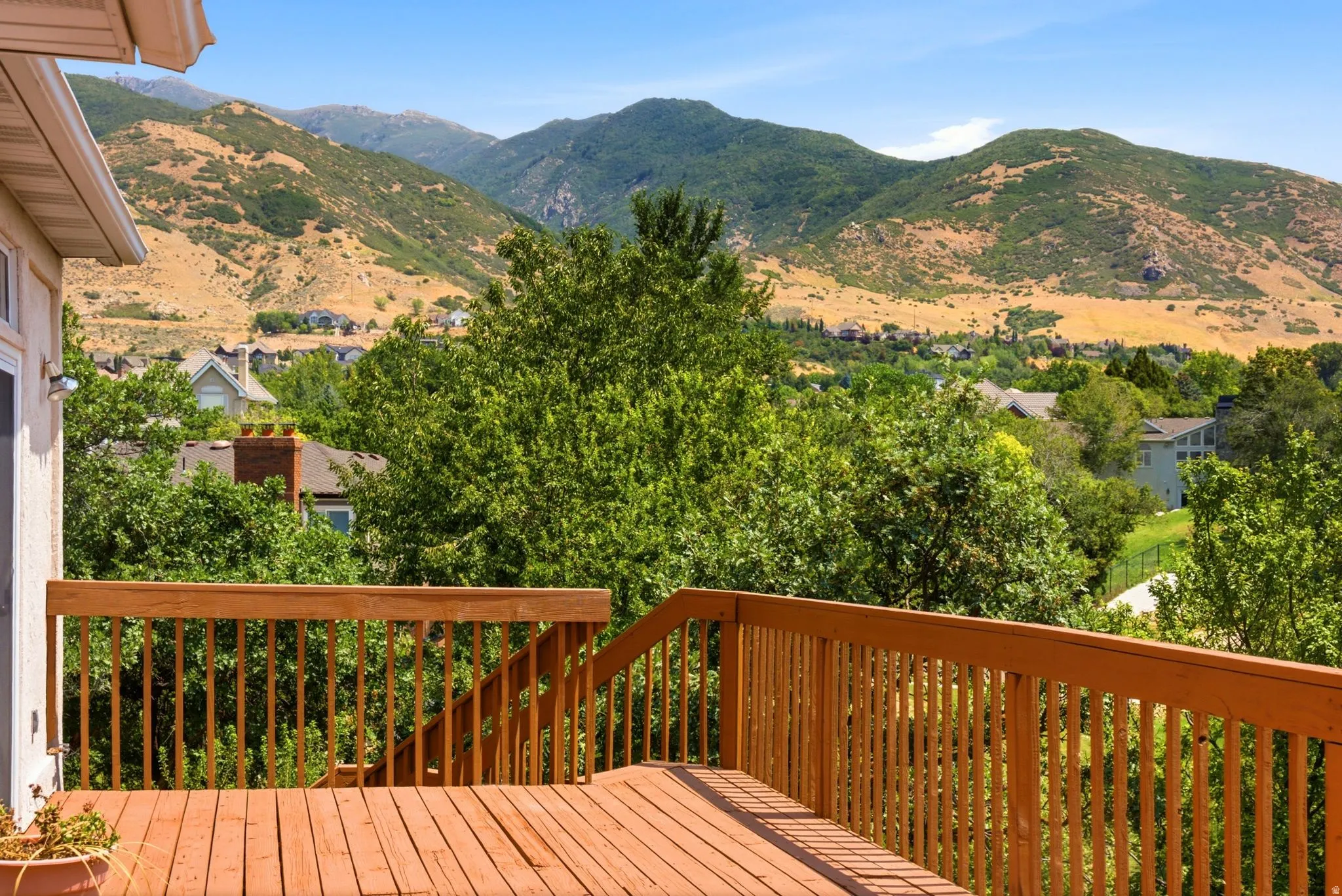 Expansive wood deck with a full railing system, offering panoramic mountain scenery and mature tree coverage