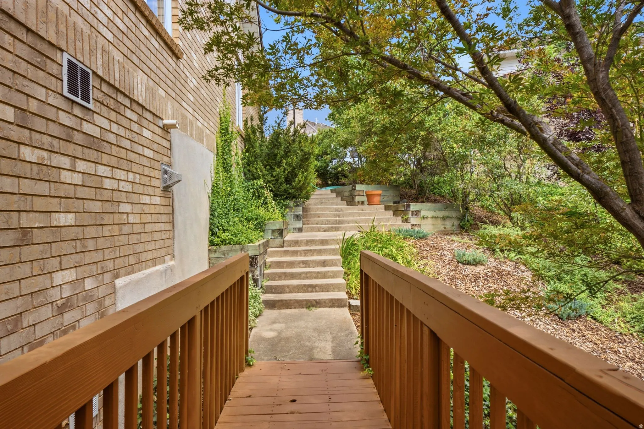 Wood deck and railing with a concrete pathway and steps