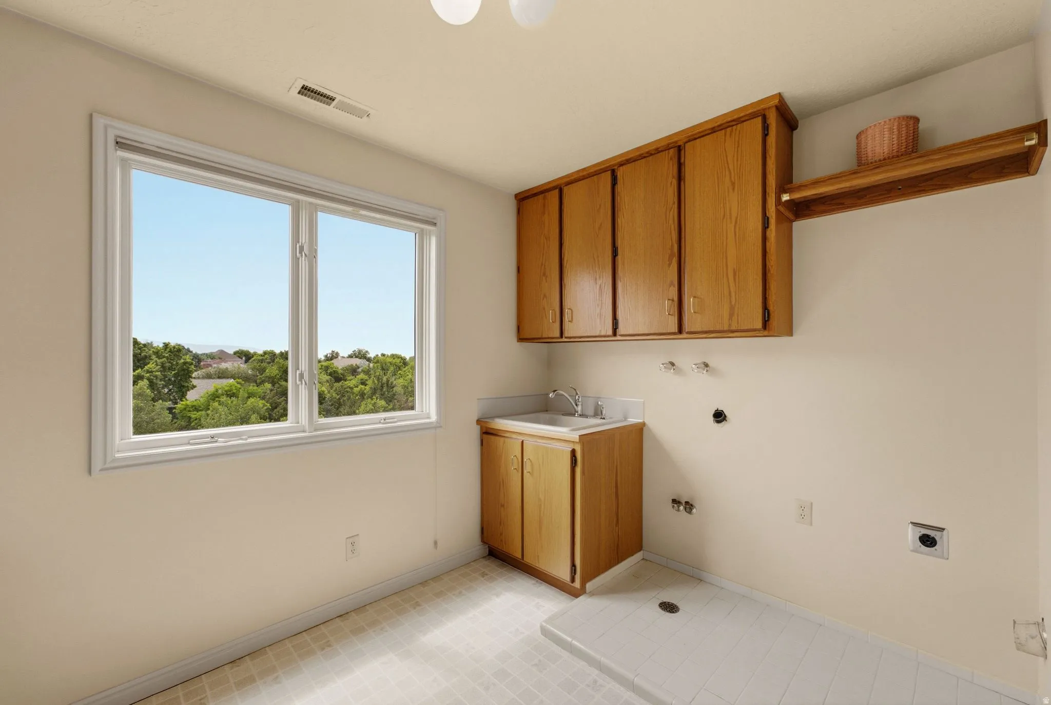 Large window, built-in cabinetry, utility sink, overhead shelving, and tiled flooring