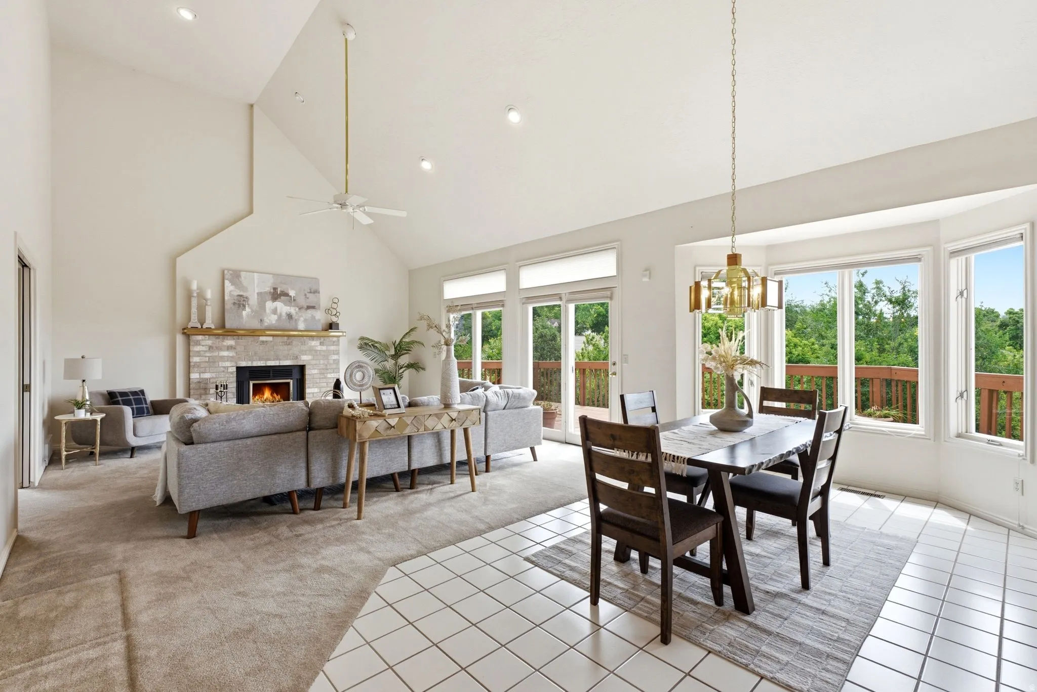 Spacious living area featuring a vaulted ceiling, recessed lighting, and a brick fireplace with a wood mantle