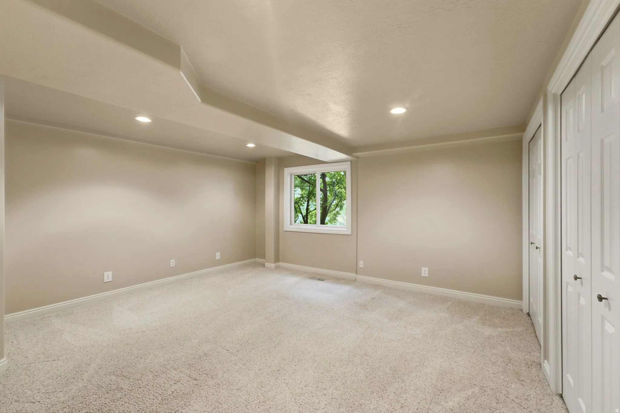 Recessed lighting, neutral-toned walls, and soft pile carpeting