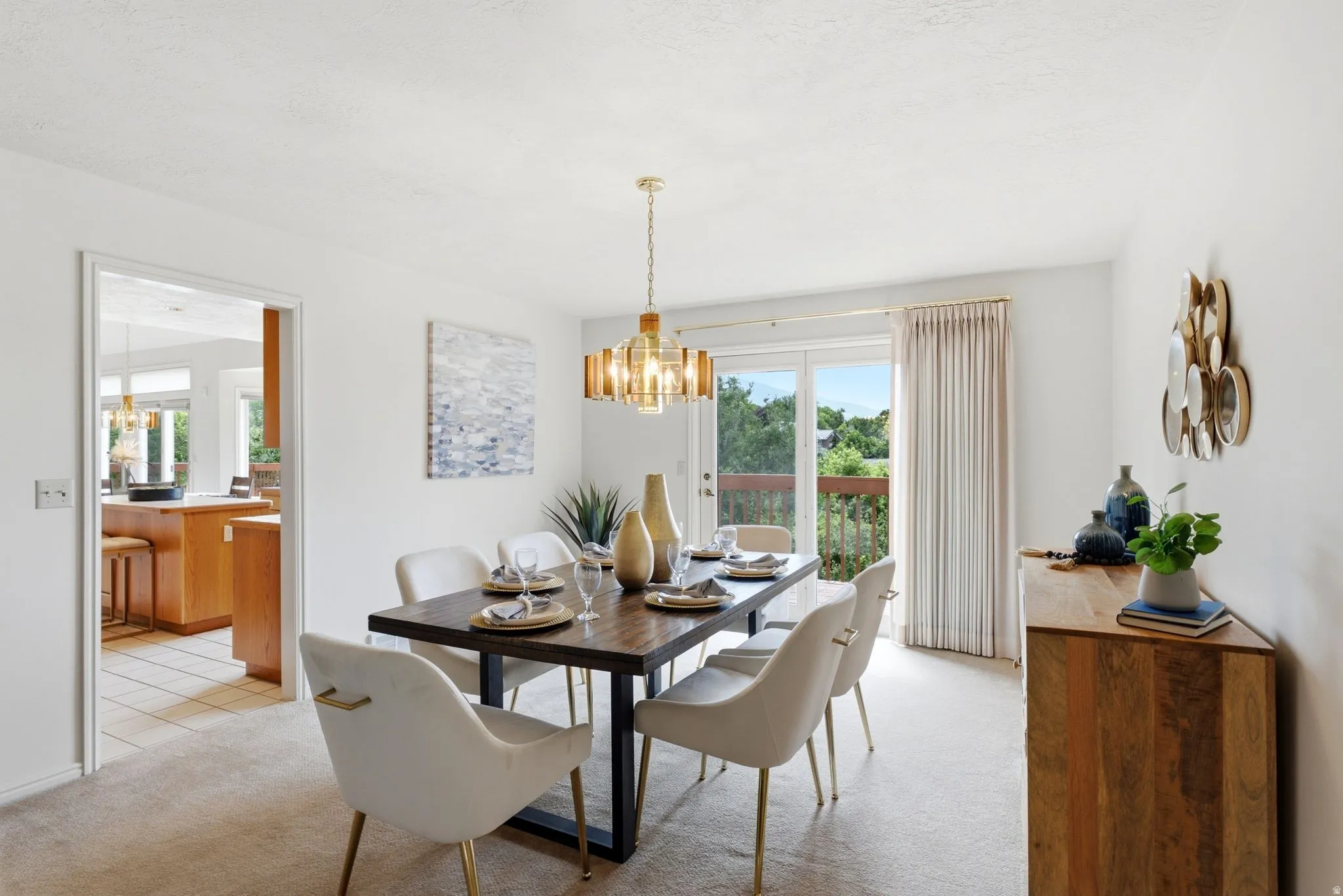 Dining area featuring a modern chandelier, light-toned carpeting, and a glass sliding door providing outdoor access