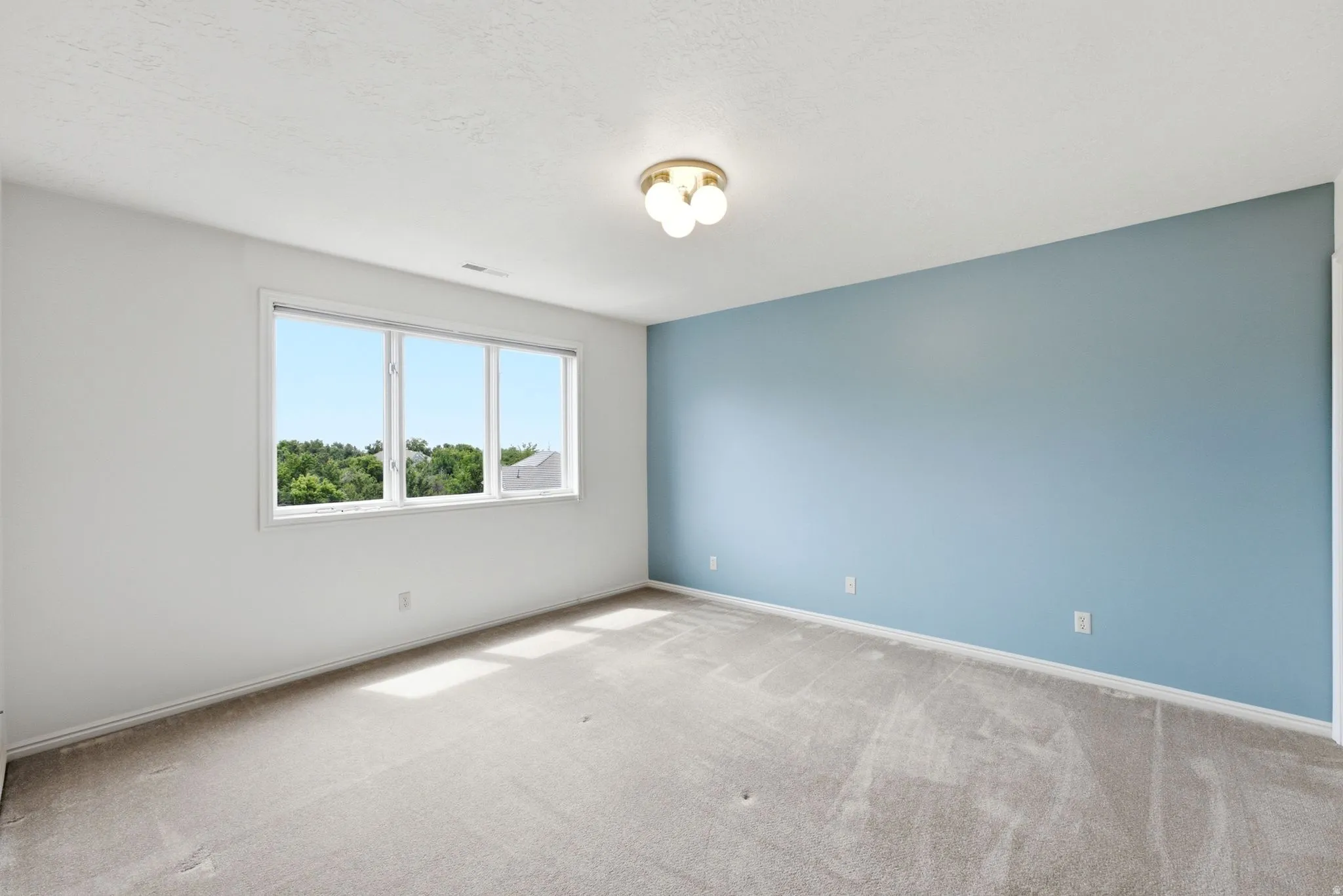 Bright interior featuring a three-panel window, light blue accent wall, white baseboards, and a semi-flush ceiling light fixture