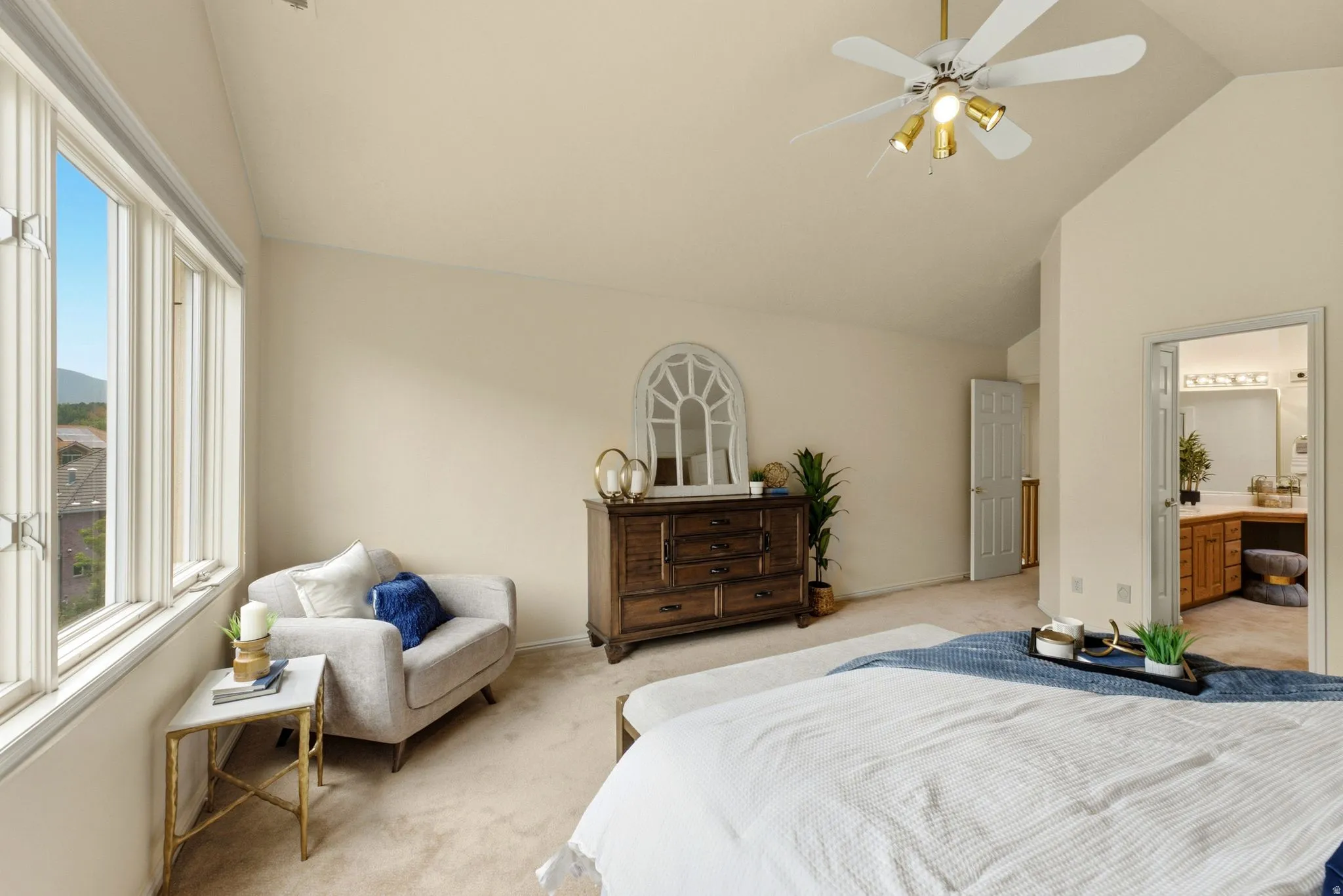 Vaulted ceiling with a ceiling fan light fixture, large bank of windows, and carpeted flooring