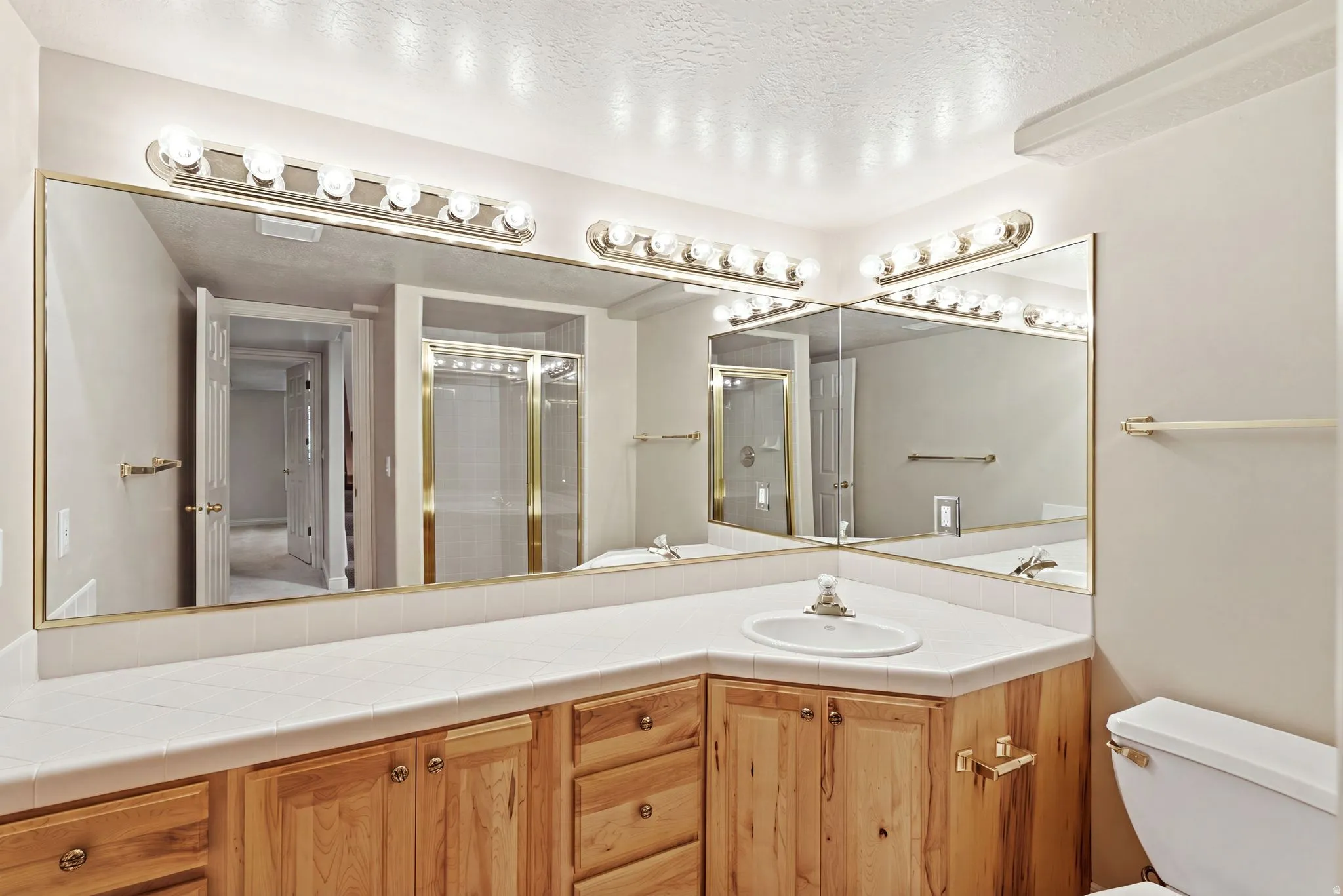 Bathroom vanity featuring light wood cabinetry, a white tile countertop, and a single undermount sink with chrome fixtures