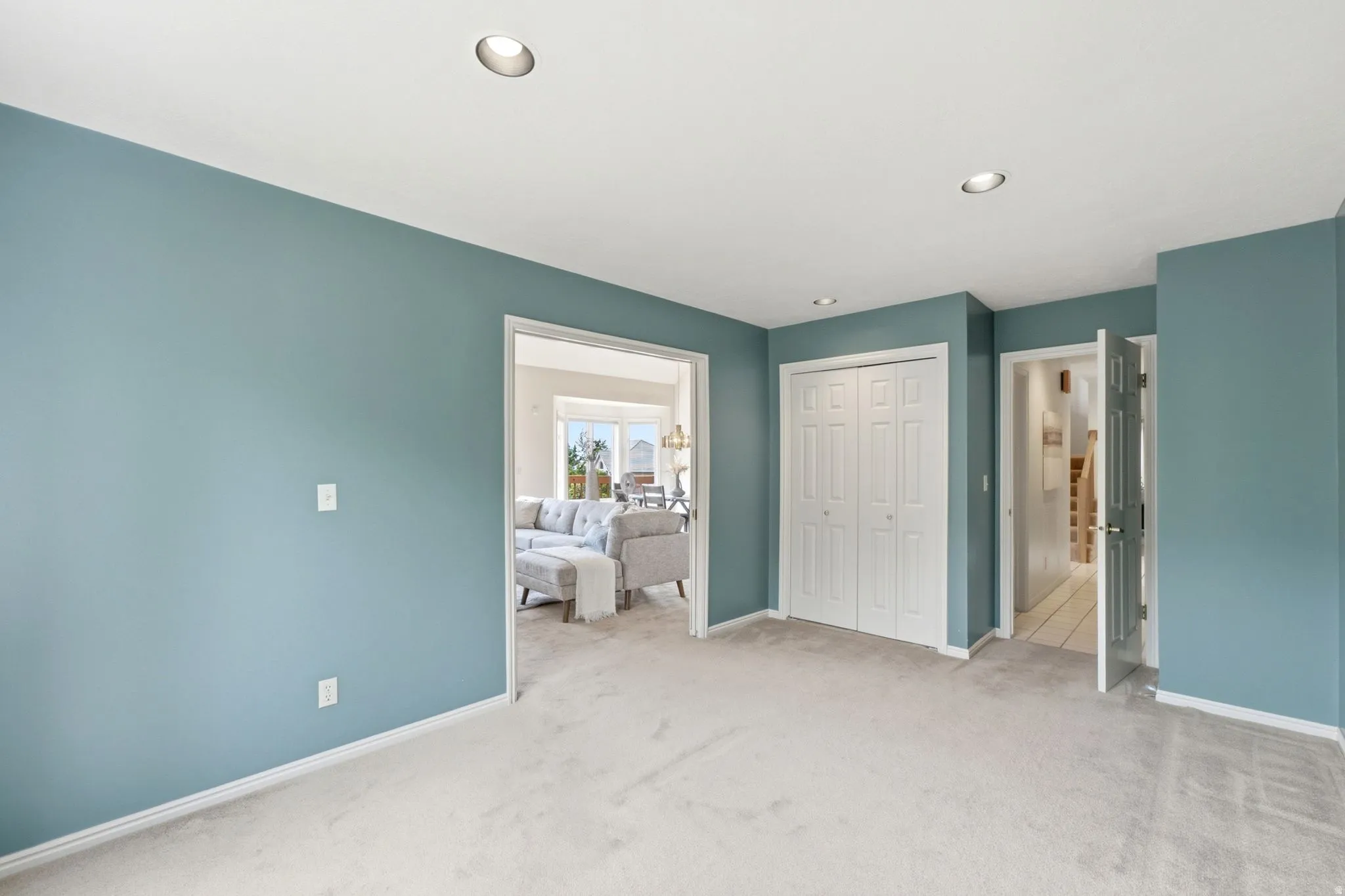 Carpeted room with recessed lighting and blue-painted walls