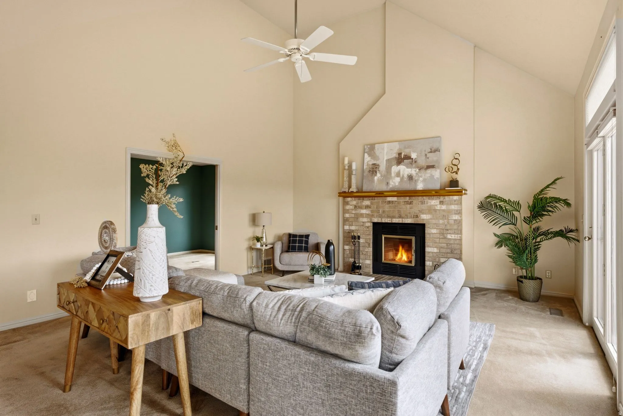 Vaulted ceilings, brick fireplace with a wood mantle, and an attached ceiling fan