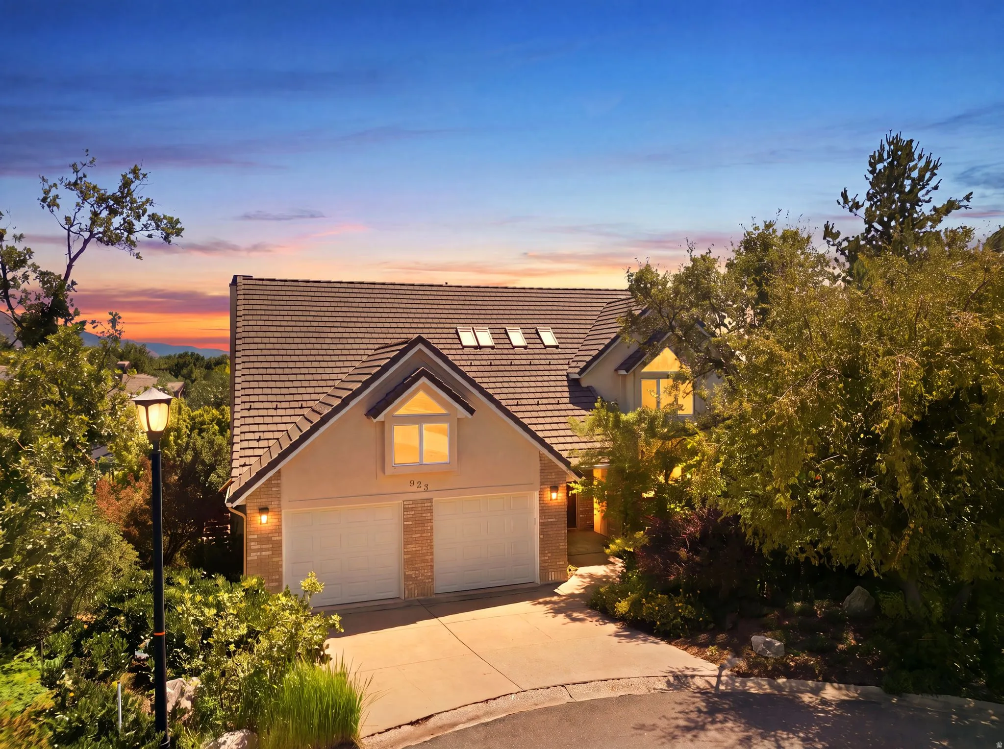 Residential property featuring a peaked roof, dormer windows, and a two-car garage