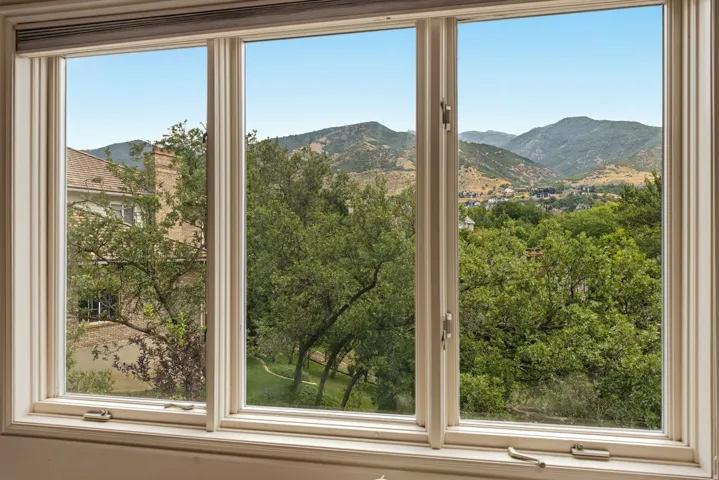 Expansive triple-pane windows frame panoramic vistas of rolling hillsides and mature oak trees