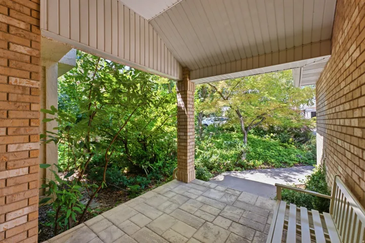 Covered entry porch featuring brick walls, an architectural post, and a paneled ceiling