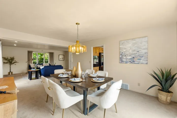 Dining area featuring a modern brass chandelier, wood-finish tabletop, and carpet flooring