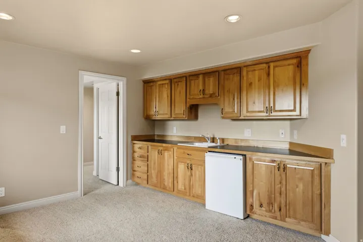 Built-in light wood cabinetry, neutral countertops, integrated sink, and recessed lighting