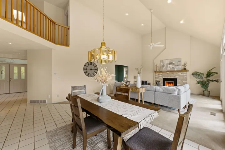Vaulted ceilings with recessed lighting, a fireplace with a brick surround, and a wood mantel