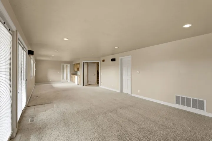 Expansive room with neutral carpet, recessed lighting, and multiple windows