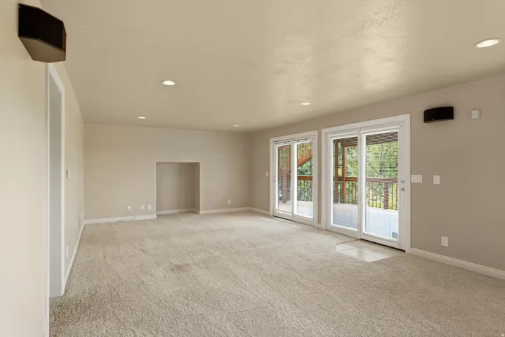 Recessed lighting illuminates the carpeted living space with a built-in alcove