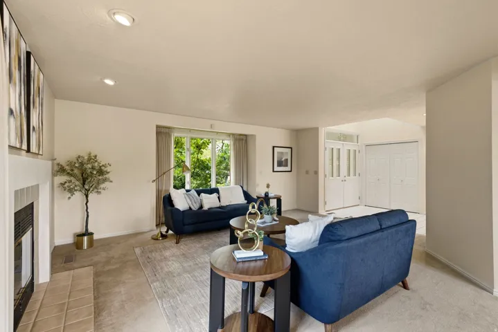 Recessed ceiling lighting, tiled fireplace, large window, carpeted flooring, and a double-door entry