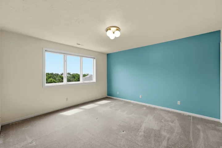 Neutral-toned walls, contrasting accent wall, ceiling-mounted light fixture, and window with exterior scenery