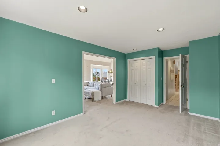 Recessed ceiling lighting, soft carpet flooring, and white bi-fold closet doors