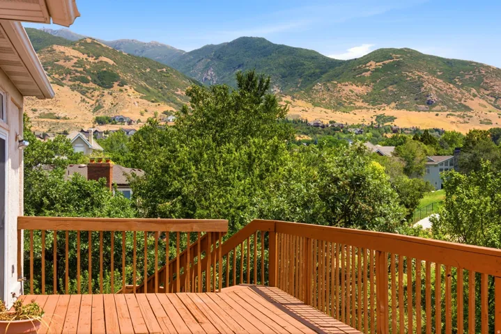 Expansive wood deck with a full railing system, offering panoramic mountain scenery and mature tree coverage