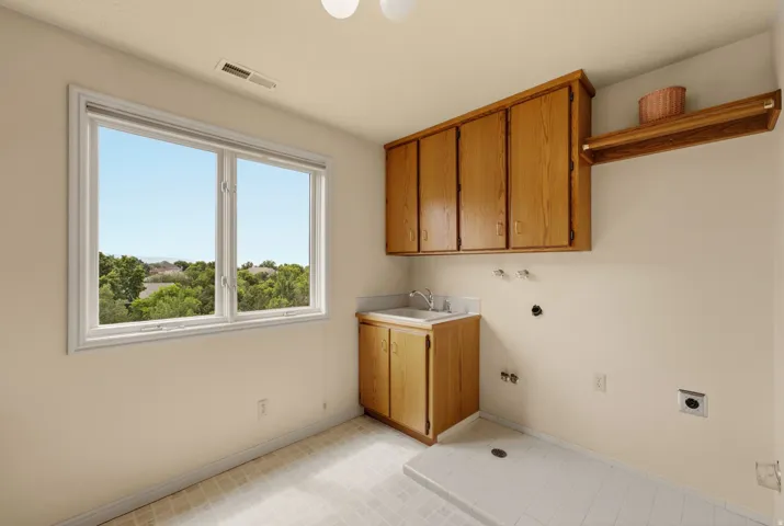 Large window, built-in cabinetry, utility sink, overhead shelving, and tiled flooring