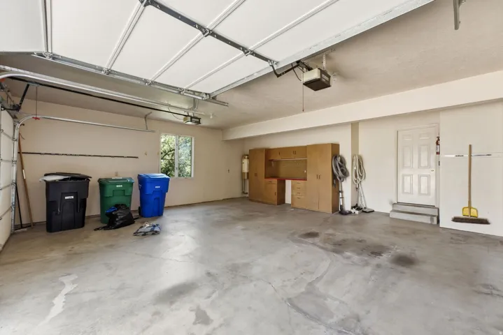 Spacious garage featuring a paneled overhead door, built-in cabinetry, a utility sink, and a multi-pane window
