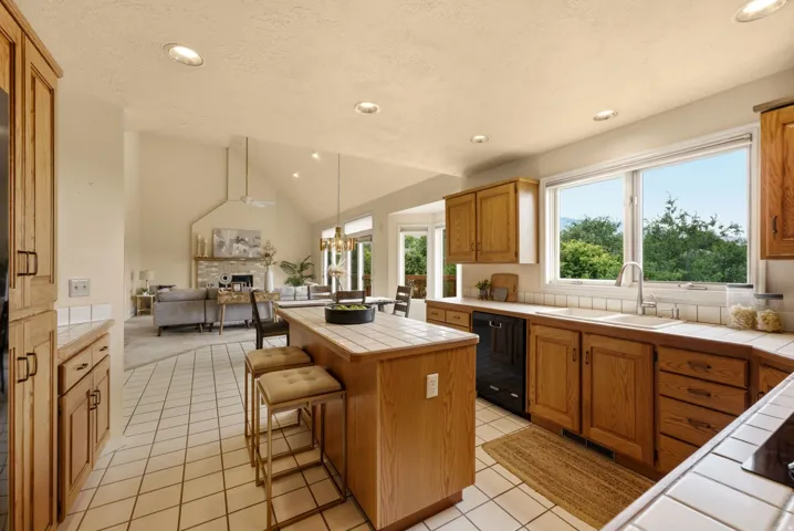 Kitchen featuring tile countertops, wood cabinetry, built-in dishwasher, recessed lighting, and a kitchen island
