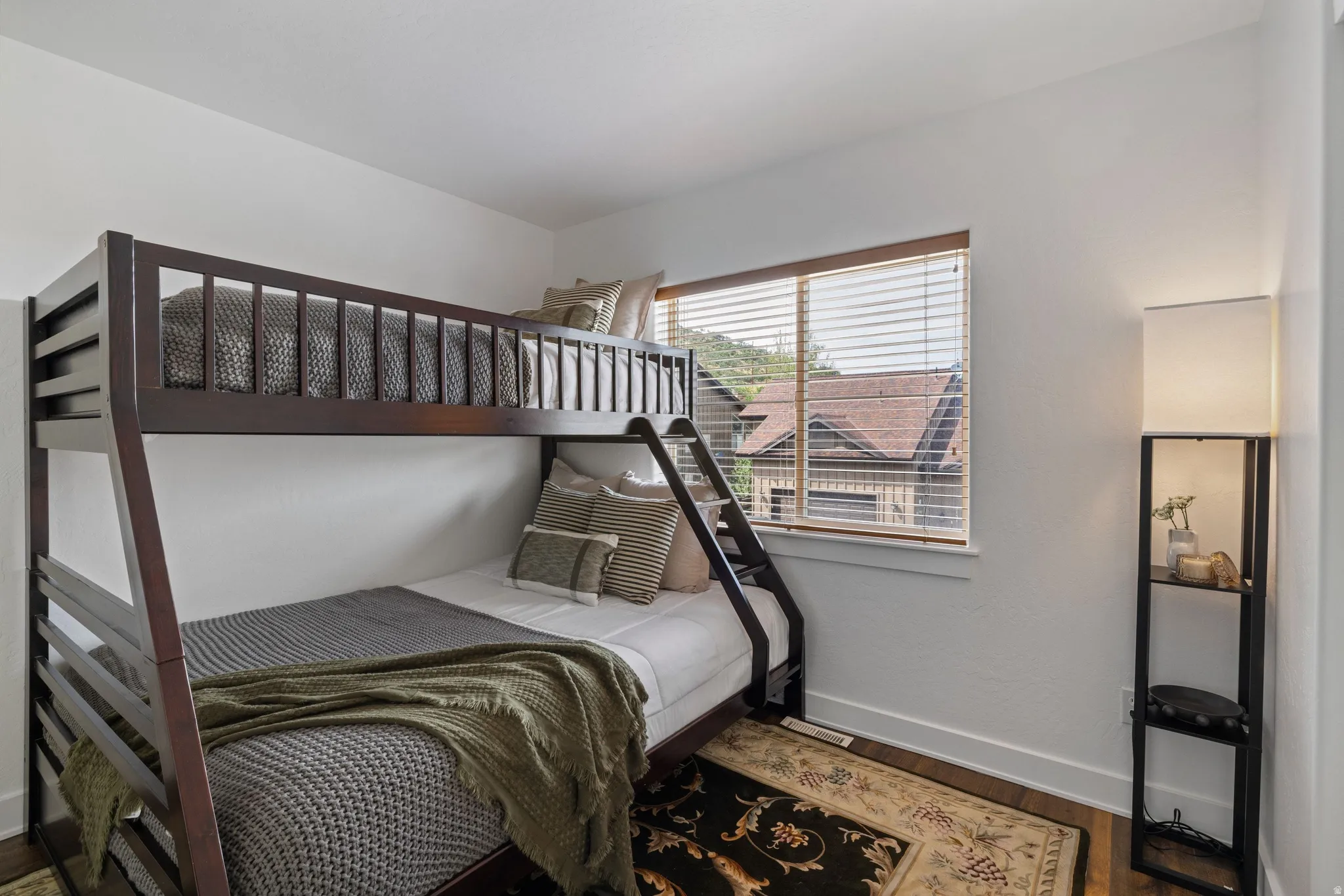 Bedroom featuring wood-finish flooring, a window with wood blinds, and white walls