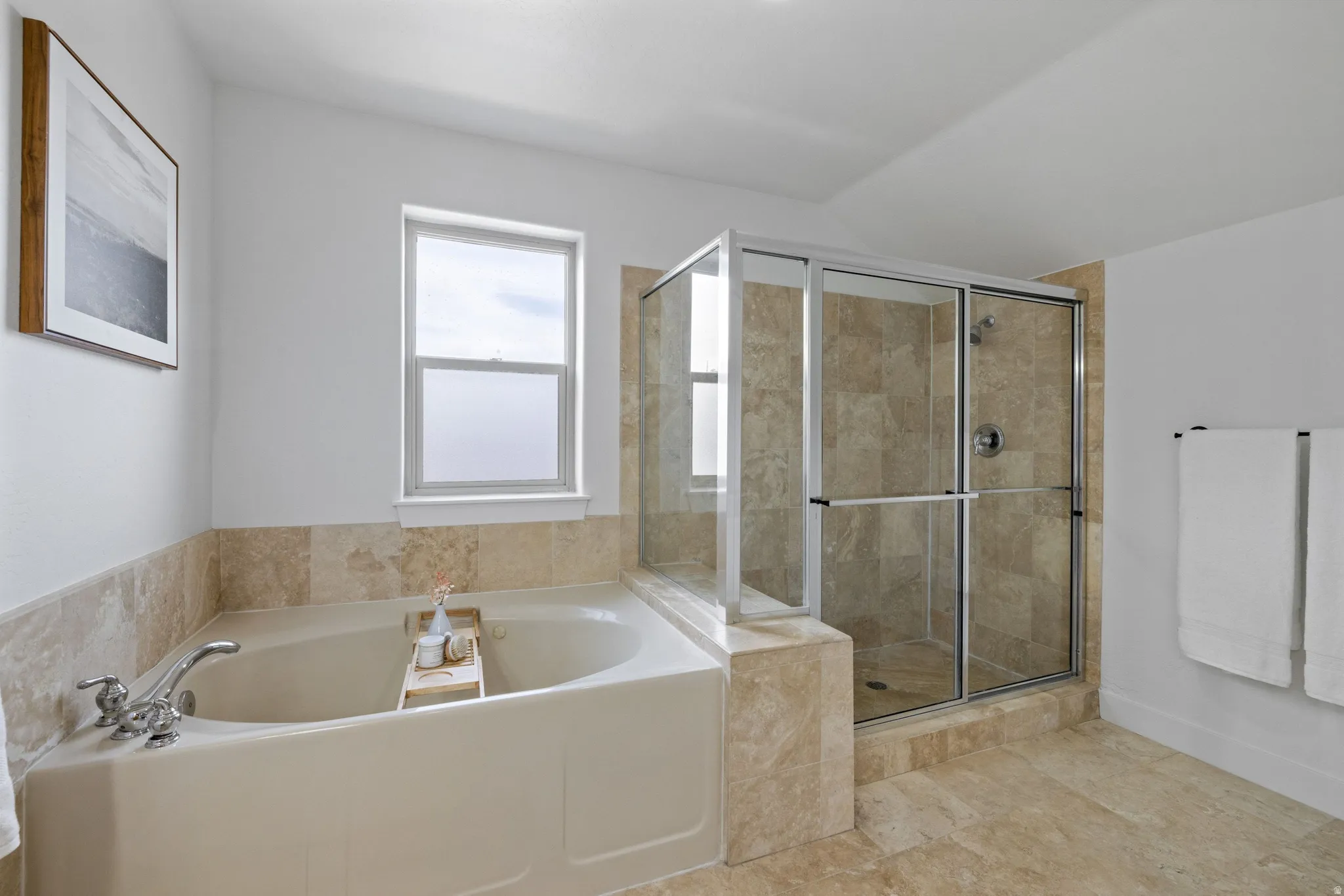 Spacious bathroom featuring a built-in corner bathtub with chrome fixtures and a separate glass-enclosed shower