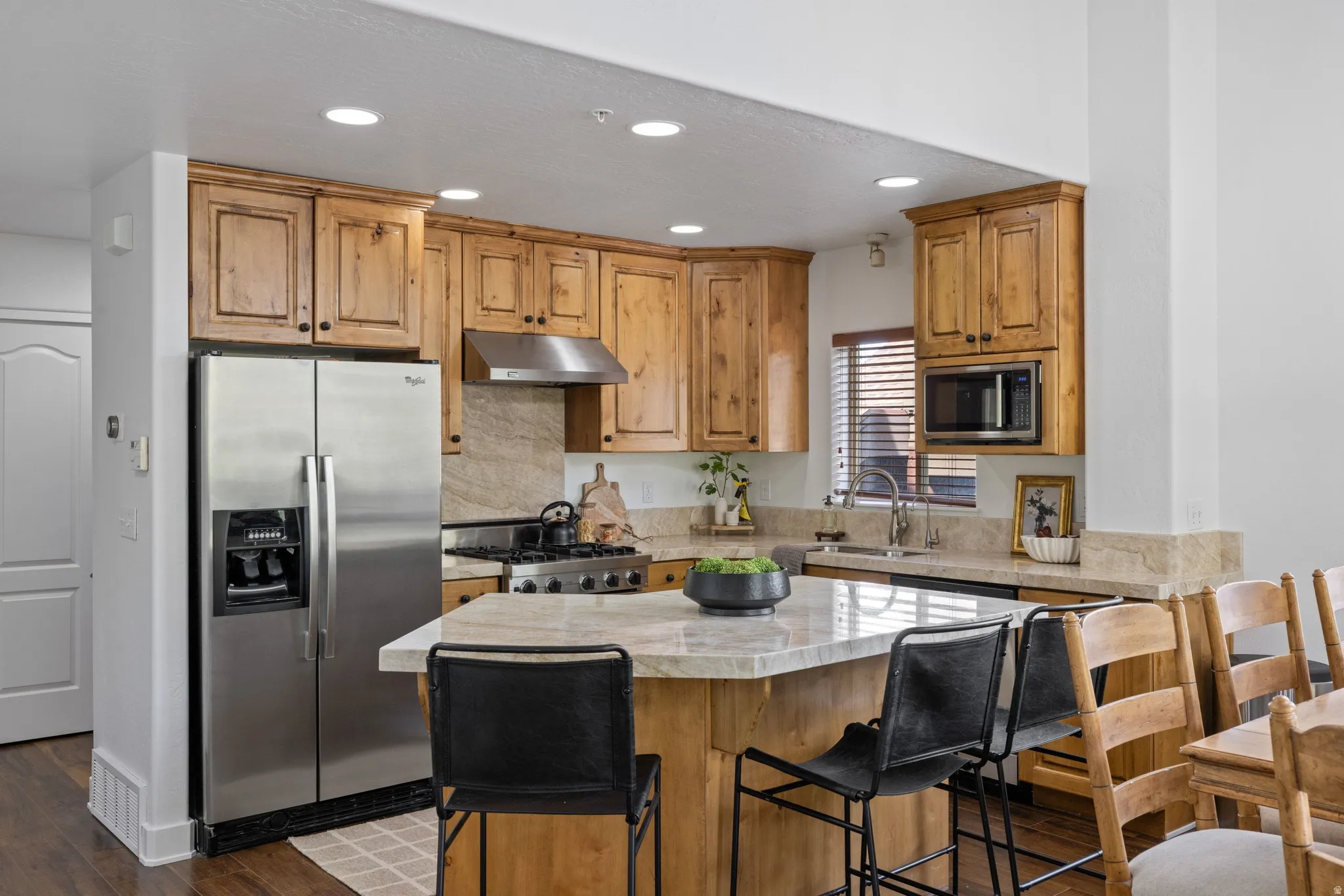 Kitchen featuring wood cabinetry, stainless steel appliances, and a central island with a stone countertop
