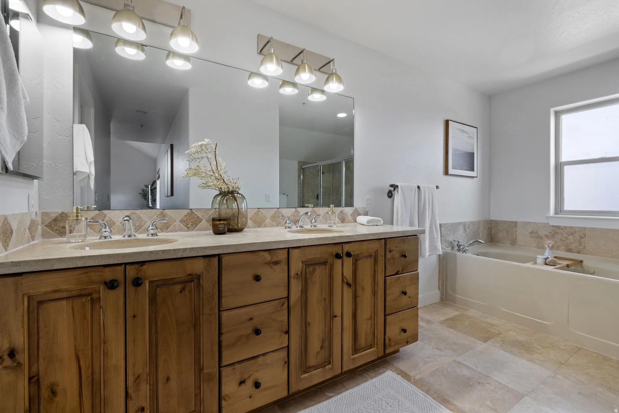 Double vanity featuring wood cabinetry with black hardware, stone countertops, and undermount sinks