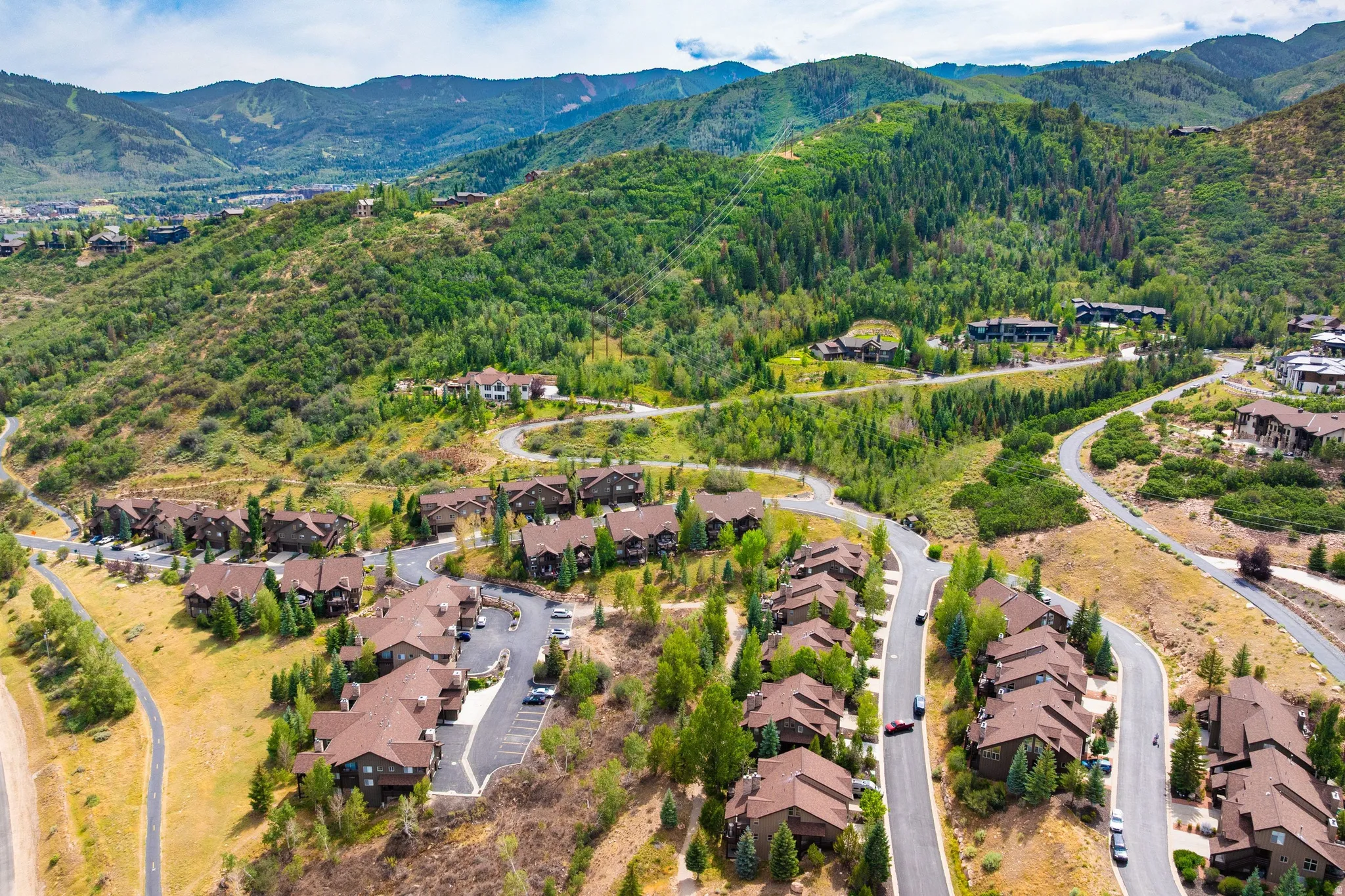 Aerial perspective showcasing a residential development nestled within a mountainous, heavily treed landscape