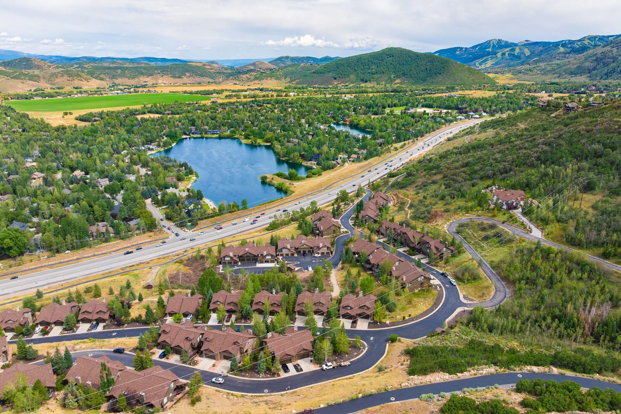 Mountainous landscape featuring a residential community with a lake and highway