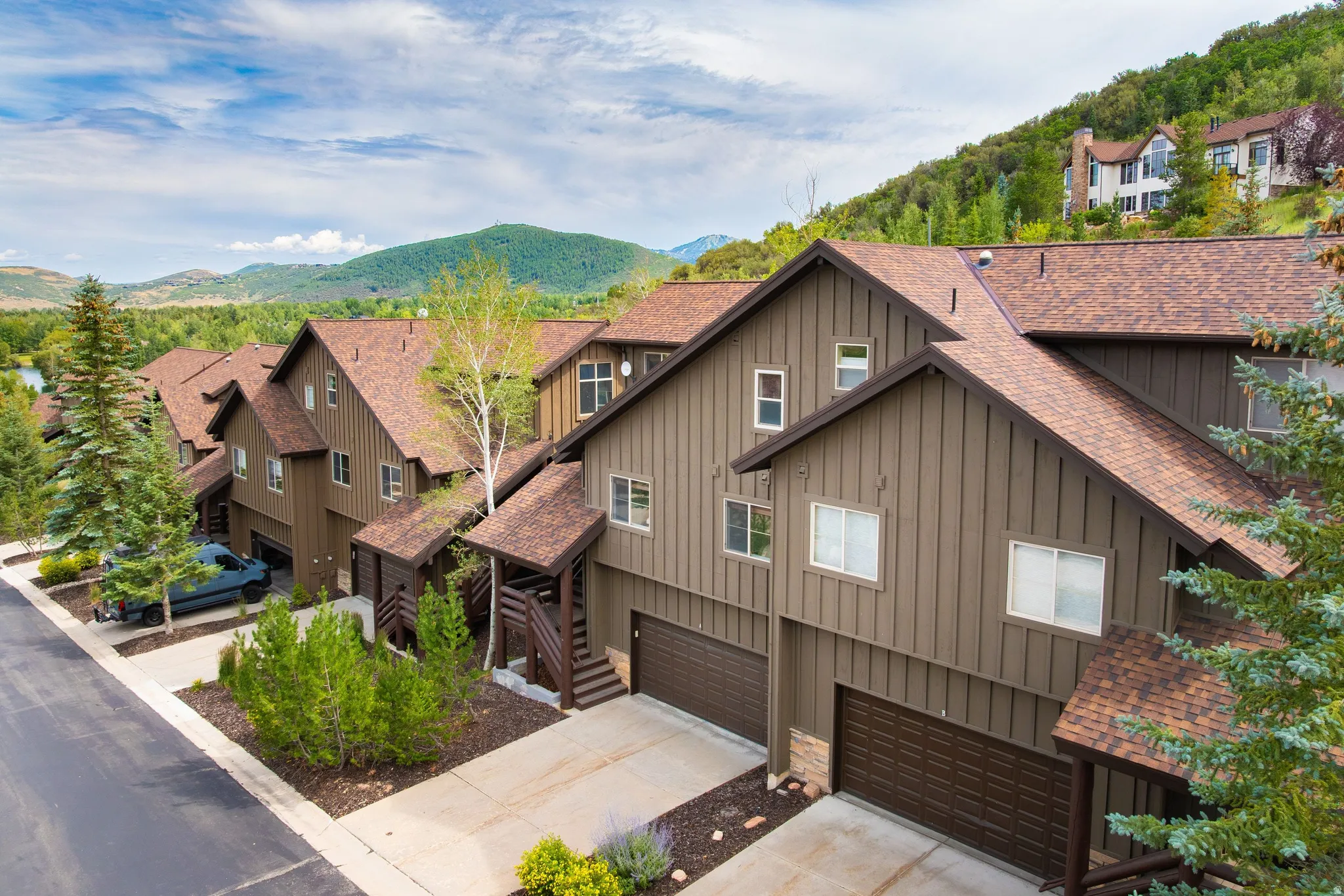 Contemporary townhome complex featuring board-and-batten siding and brown shingle roofs