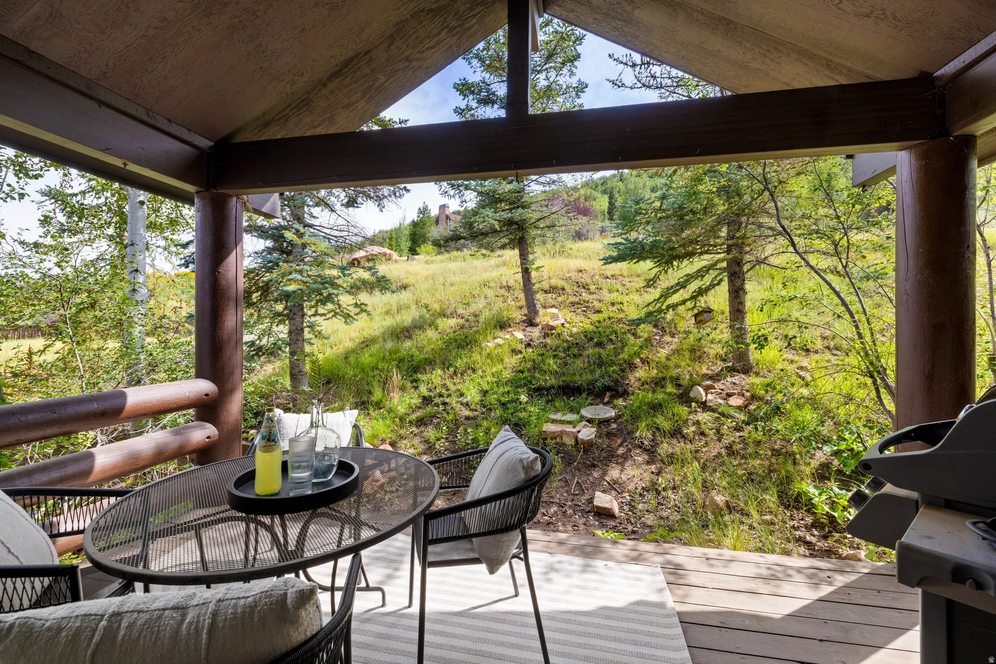 Covered outdoor deck with wood-finish flooring and log beam construction