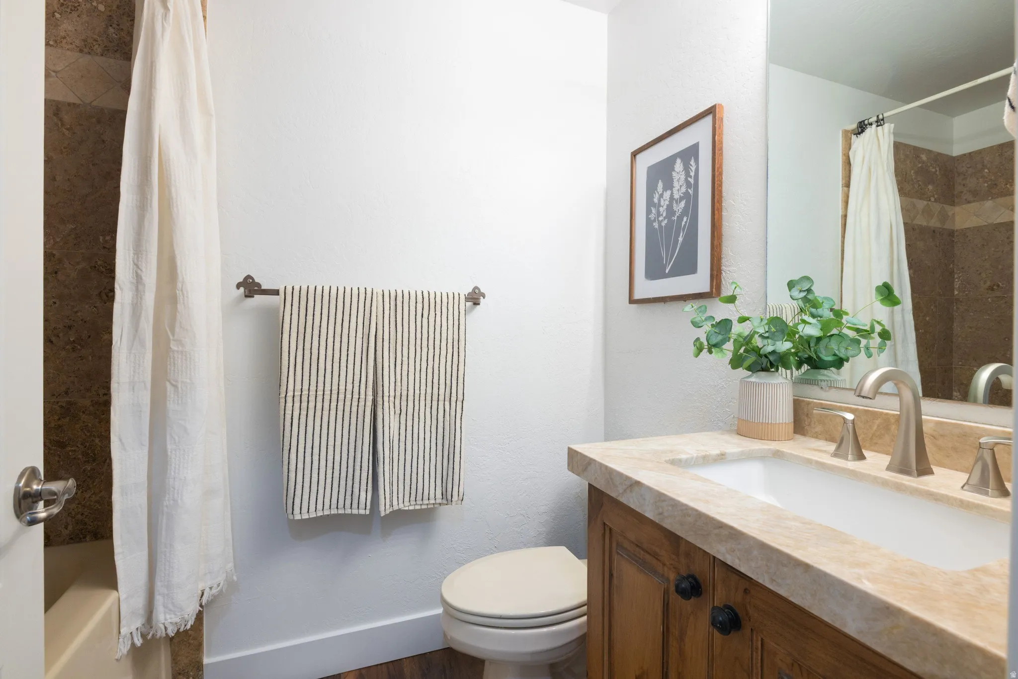 Bathroom featuring a single vanity with wood cabinetry, a stone countertop, and an undermount sink