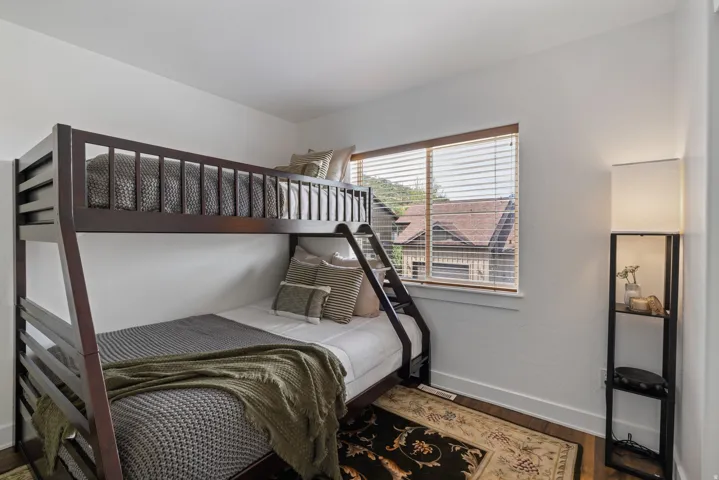 Bedroom featuring wood-finish flooring, a window with wood blinds, and white walls