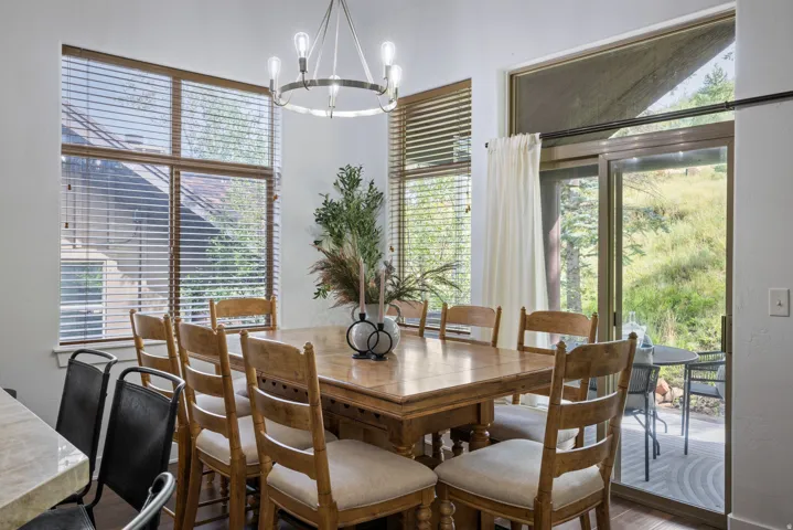 Dining area featuring wood-finish flooring, a contemporary chandelier, and large windows with blinds