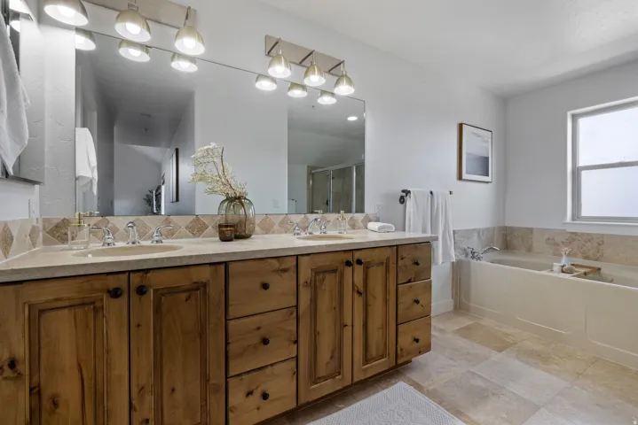 Double vanity featuring wood cabinetry with black hardware, stone countertops, and undermount sinks