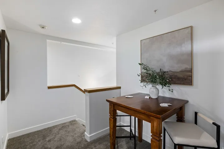 Carpeted hallway with white walls, wood handrail, and recessed ceiling lighting