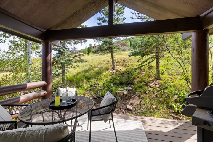 Covered outdoor deck with wood-finish flooring and log beam construction
