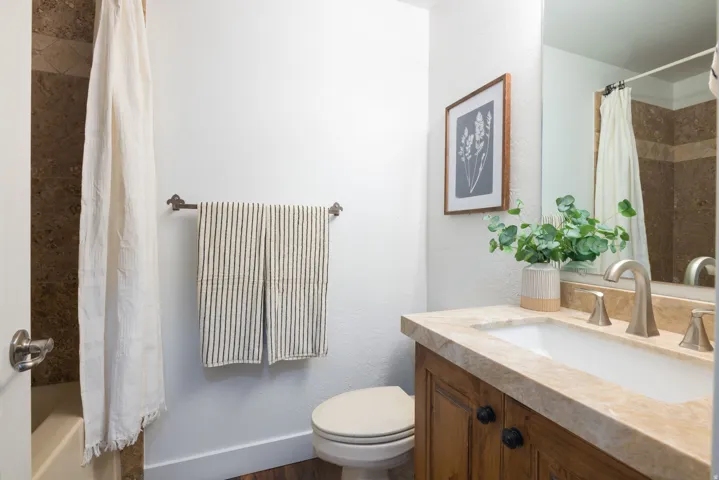 Bathroom featuring a single vanity with wood cabinetry, a stone countertop, and an undermount sink