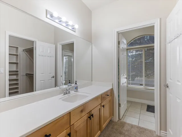 Bedroom #2 en-suite bathroom featuring warm wood-finish cabinetry with separate tub & shower and walk in closet